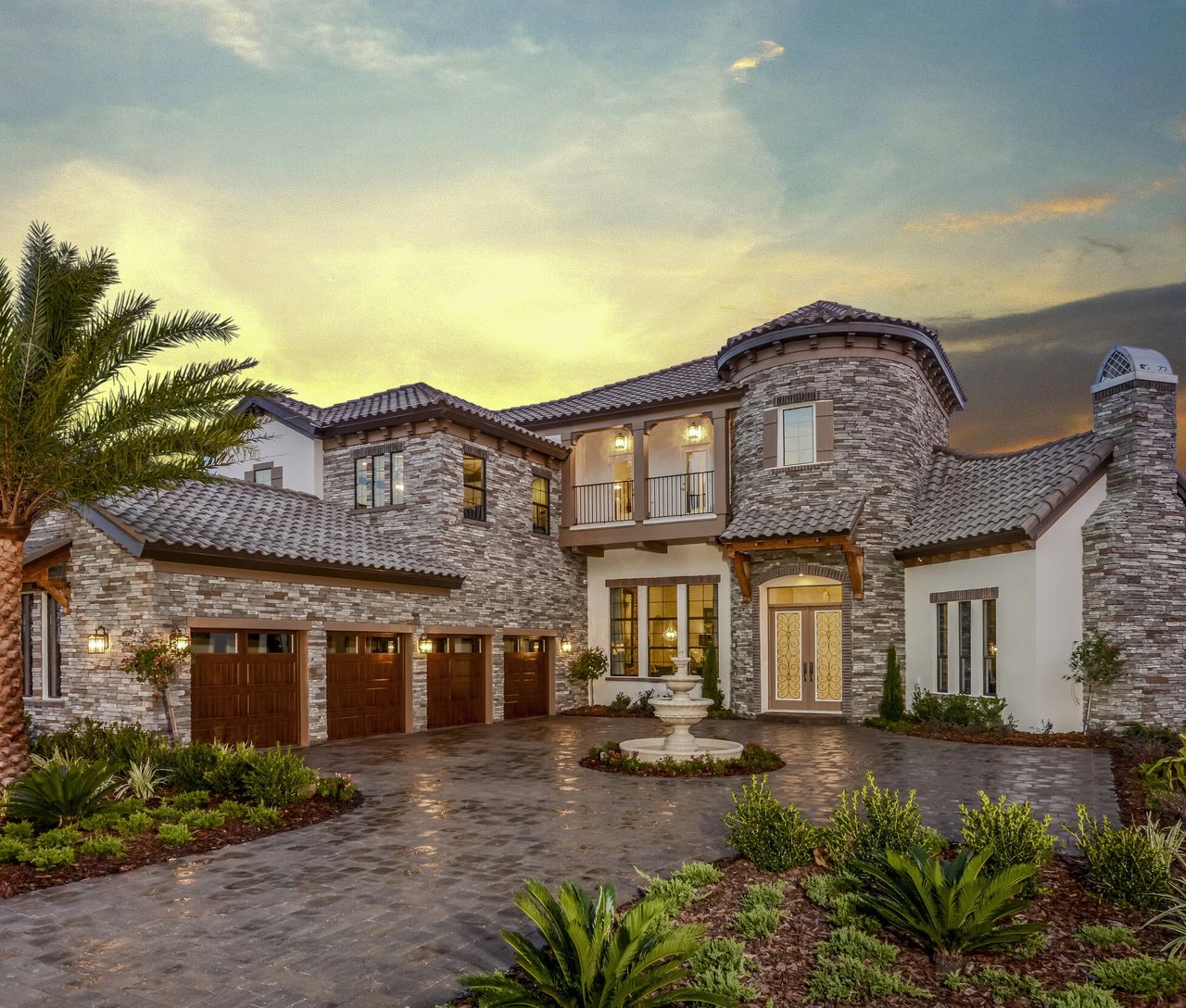 A Cornerstone project at golden hour — stonework, paver drive, and lush Florida planting
